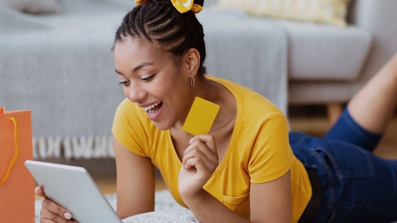 A smiling woman with a card and a tablet