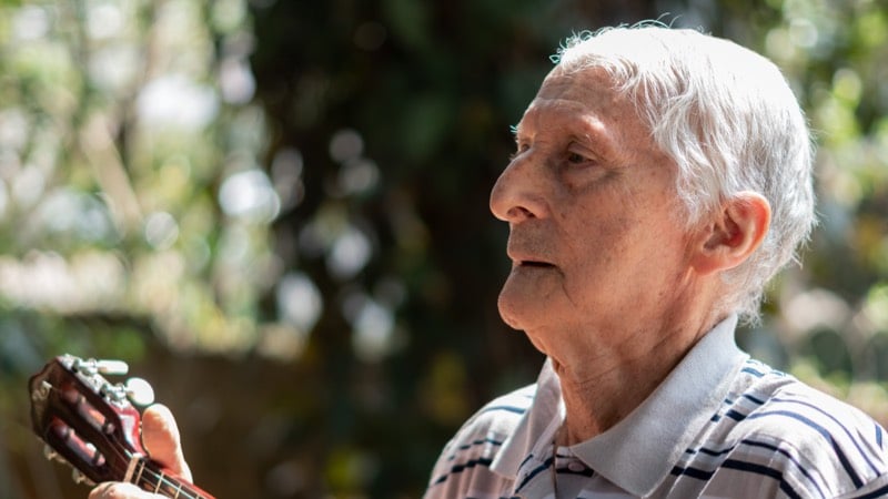 Imagem exibe um idoso tocando instrumento musical