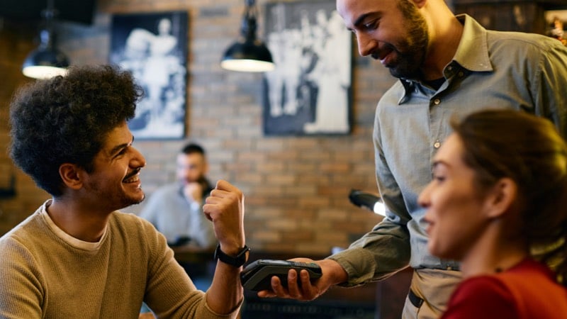 Imagem exibe homem efetuando pagamento por aproximação com smart watch