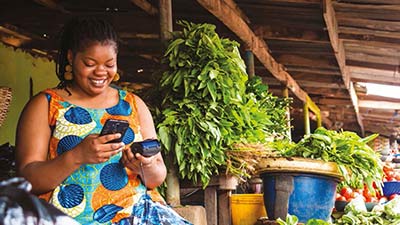 Mulher sorrindo enquanto realiza um pagamento por aproximação com seu smartphone