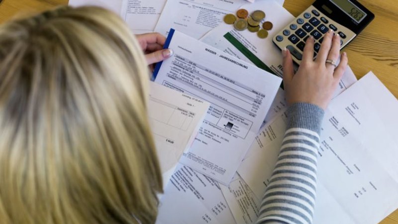 Mulher organizando suas finanças com documentos e sua calculadora