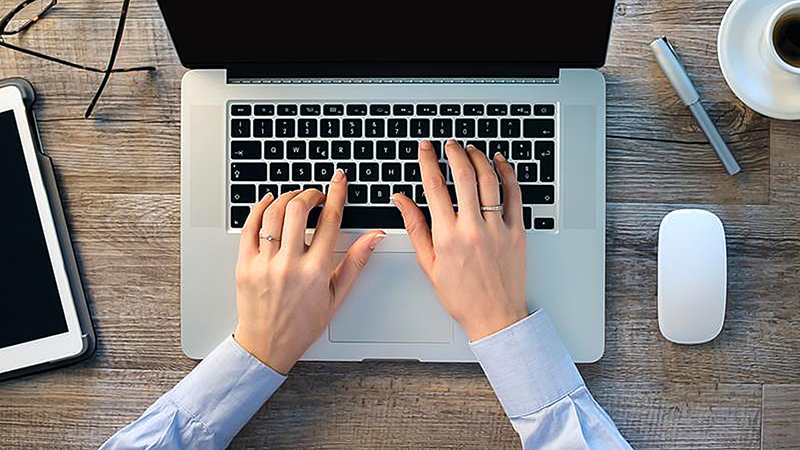 Man's hands hovering over laptop keyboard.