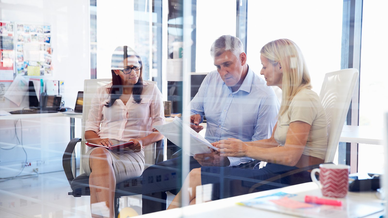 Three people seated in an office discussing work-related issues.