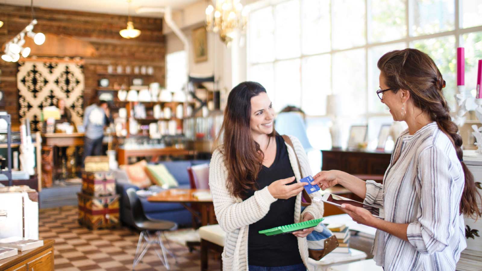 Woman handing over her Visa credit card to shop cashier.