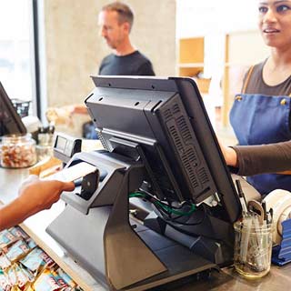Cashier talks to a customer as the customer taps to pay with their phone.