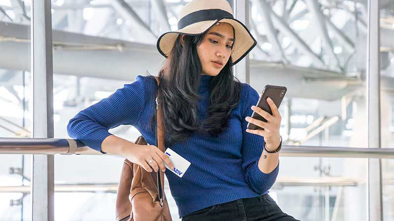 A woman at the airport pays for something on her phone with a Visa card