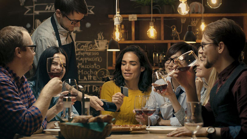 Woman paying for dinner with her friends in a restaurant