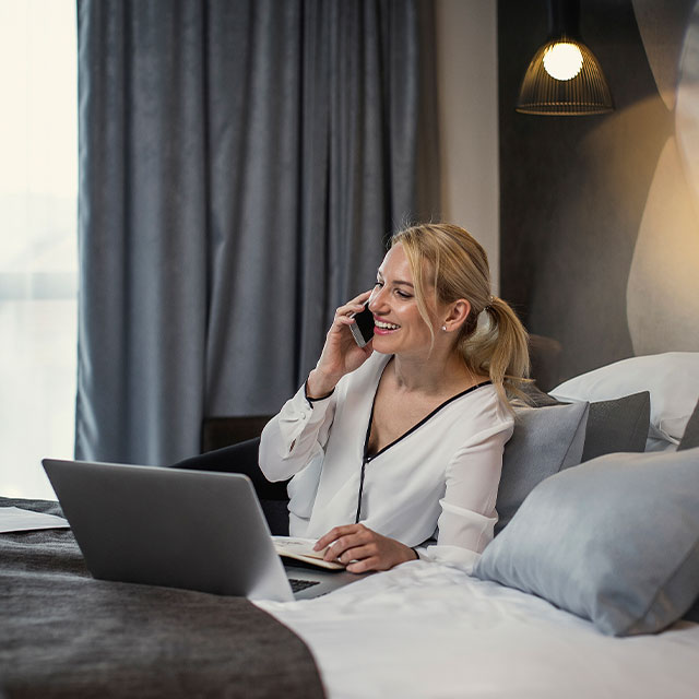 Mujer trabajando con su computadora mientras habla por celular