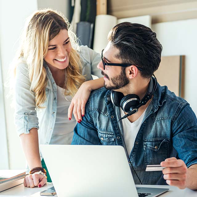 Personas felices haciendo un pago con tarjeta a través de una notebook