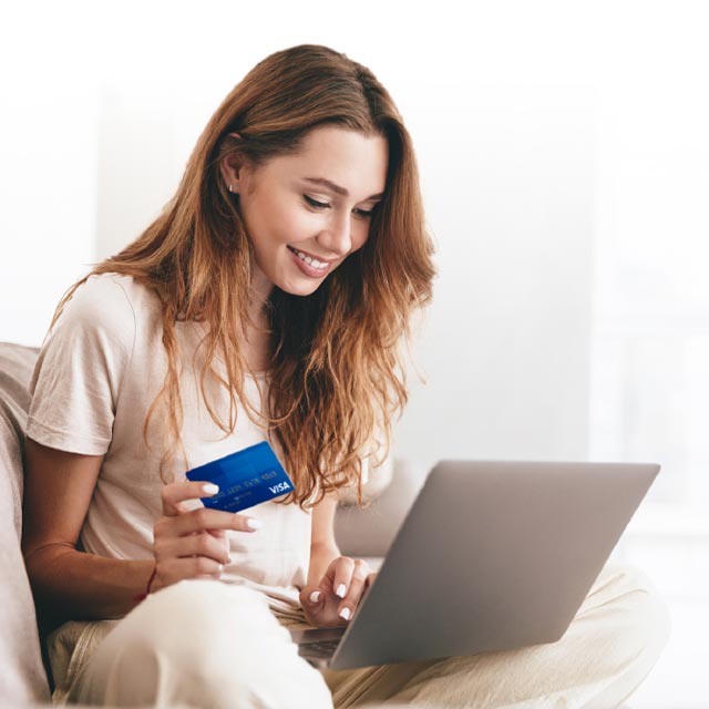 Mujer utilizando laptop con tarjeta de crédito en mano