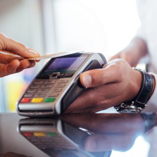Pessoa pagando com cartão em máquina contactless.