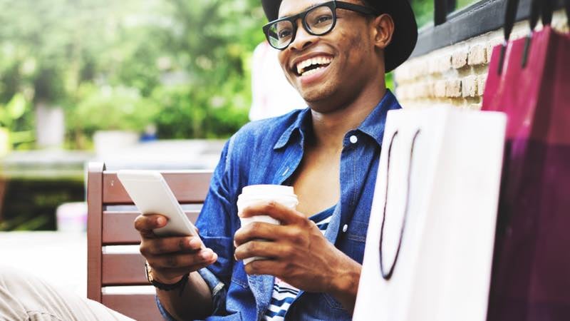 Homem sorrindo com celular na mão.