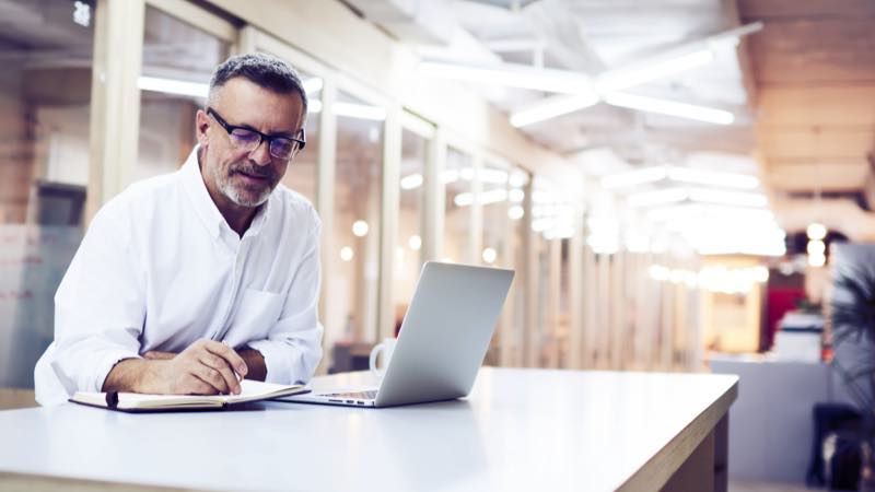 Homem trabalhando com notebook e caderno