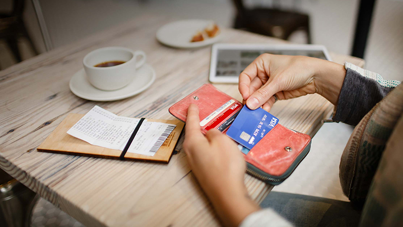 Pessoa retira cartão da carteira para pagar conta