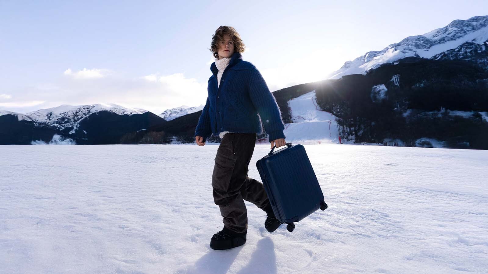Homem caminhando na neve com bagagem na mão