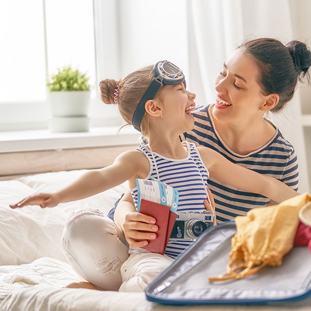 Mãe e filha sorrindo com passagens de viagem na mão