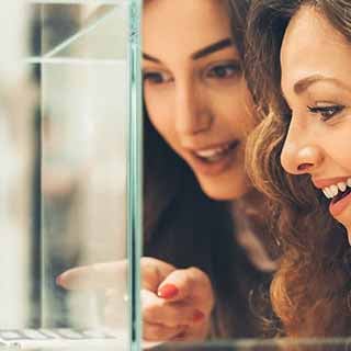 Duas mulheres sorrindo em frente a uma vitrine