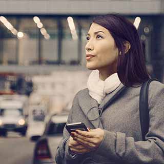 Mulher no estacionamento com celular na mão