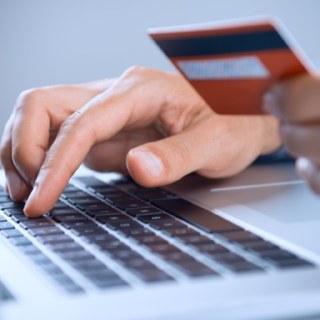 Pessoa faz compras online com cartão na mão