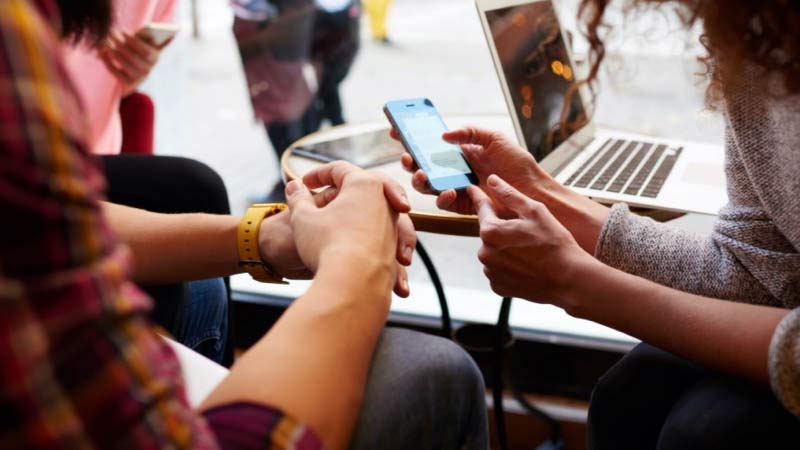 Pessoas num café olhando a tela do celular