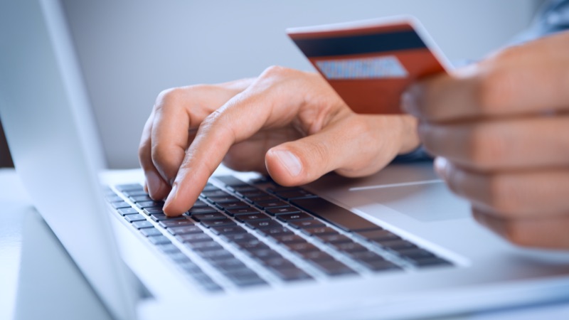 Pessoa faz compras online com cartão na mão
