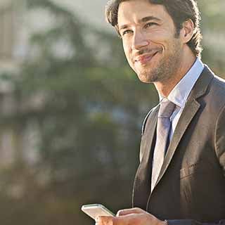 Homem de terno sorrindo com celular na mão