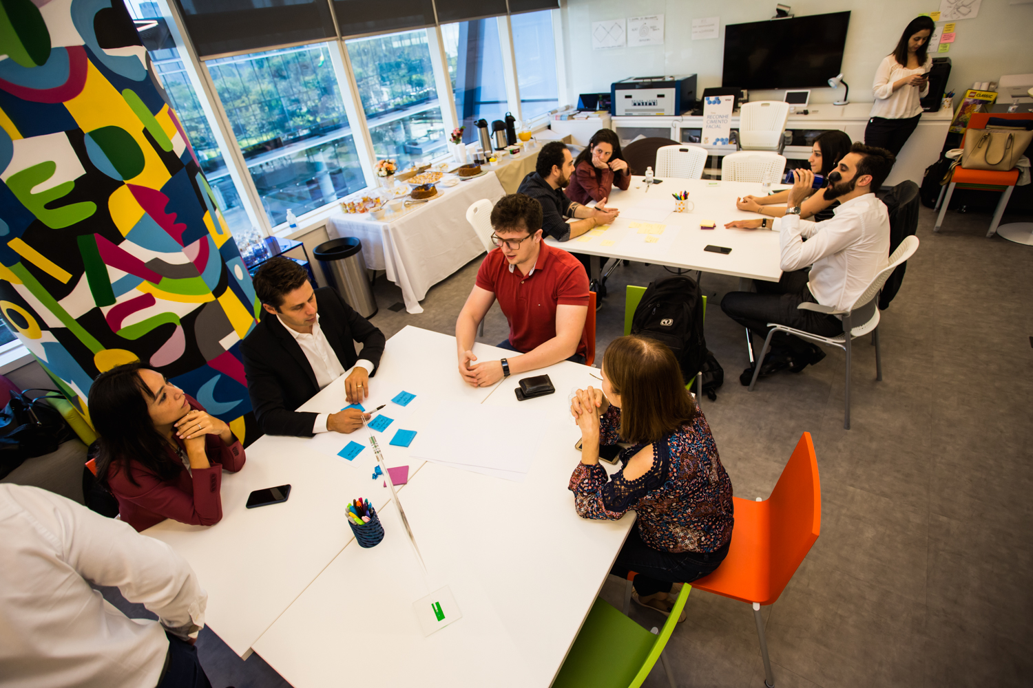 Pessoas em reunião num escritório decorado com arte e objetos coloridos