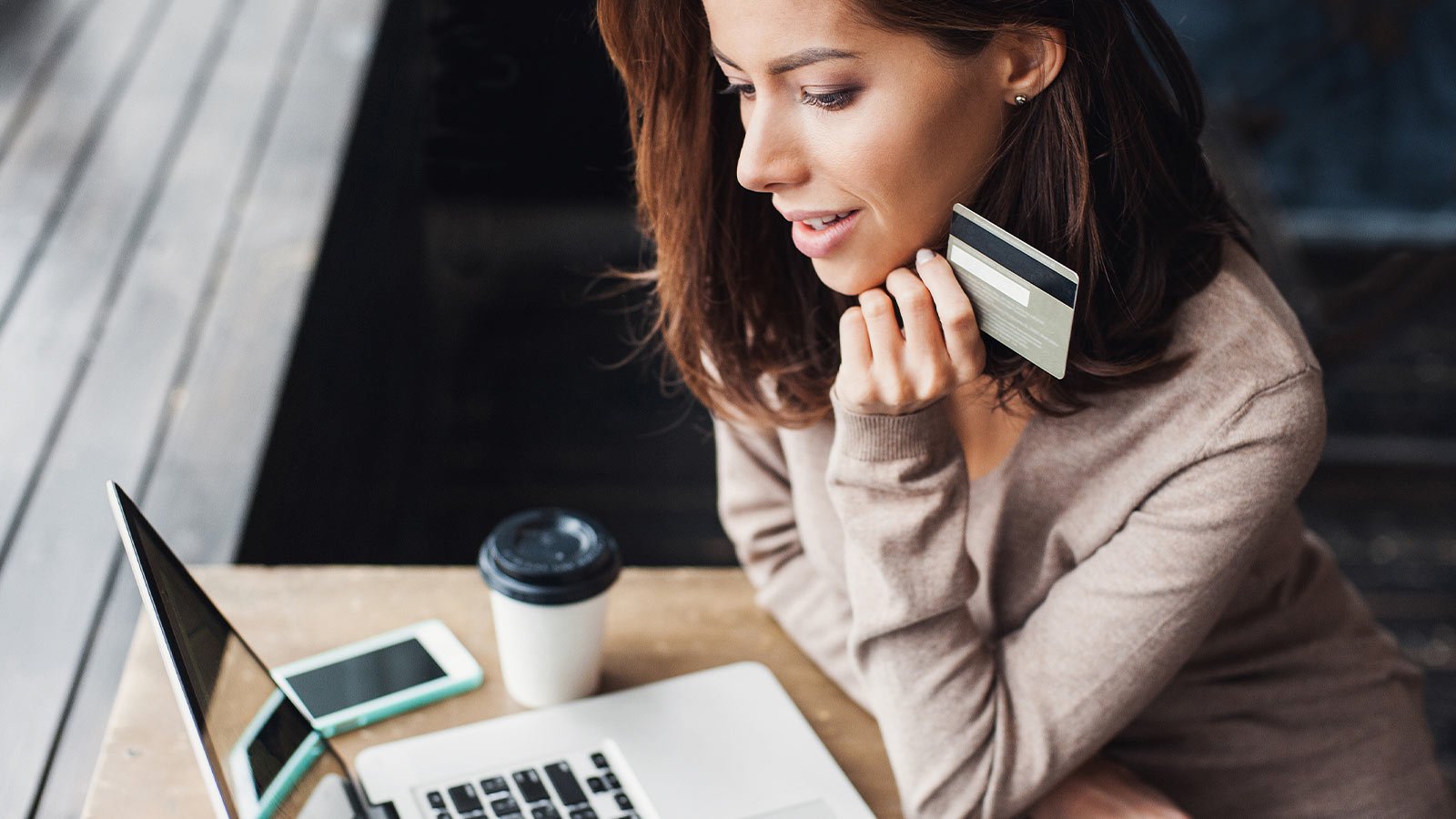 Mulher de perfil corporativo com cartão em frente ao notebook