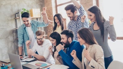 Grupo de pessoas comemorando em frente ao computador.