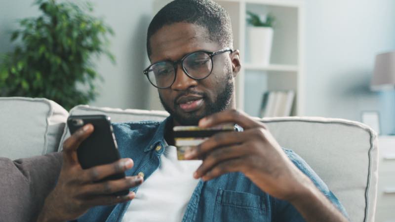 Homem com smartphone e cartão em mãos