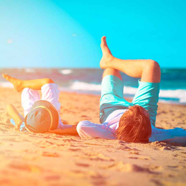 Duas pessoas deitadas na areia da praia