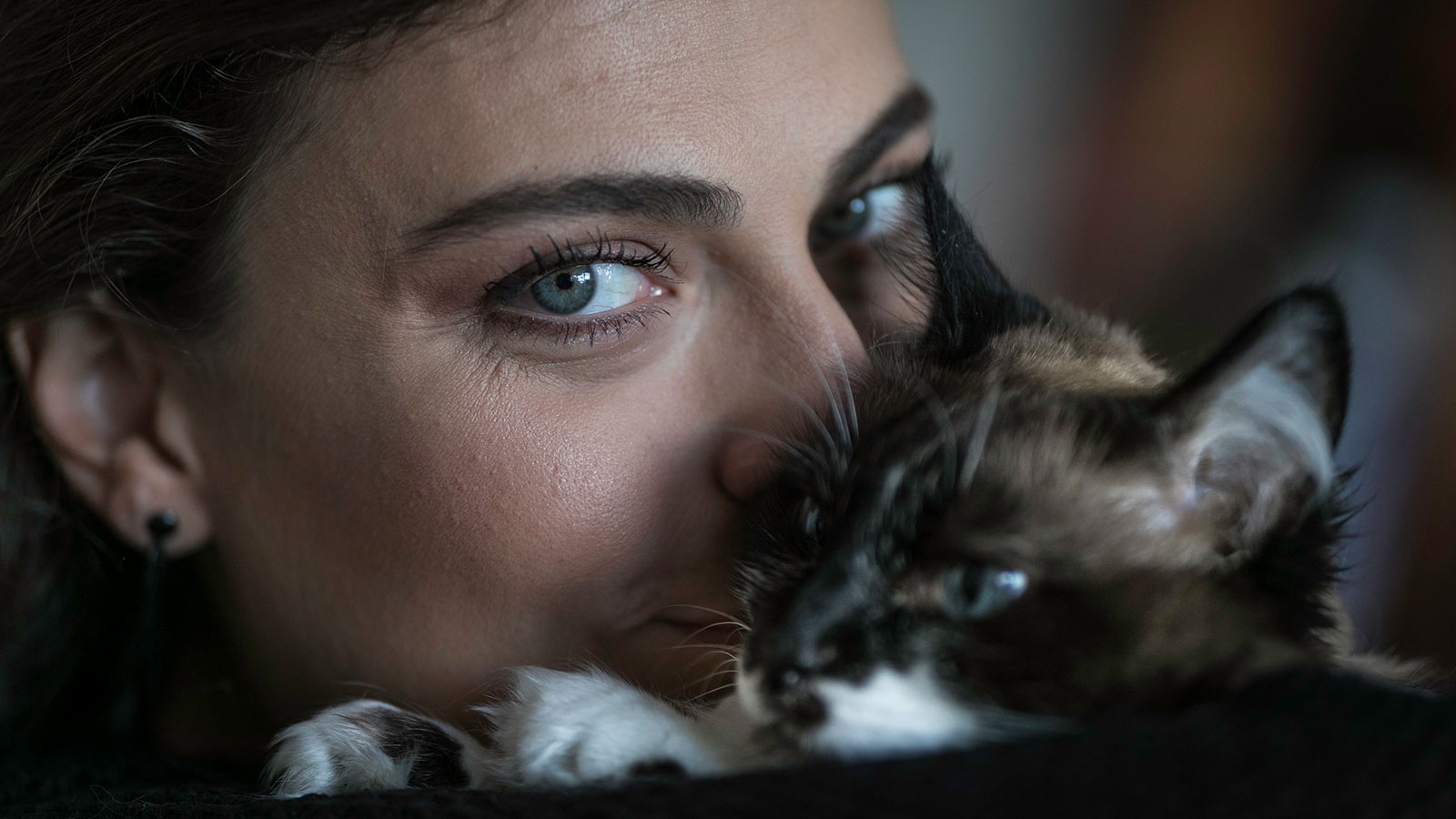 Mulher com um gato próximo ao rosto
