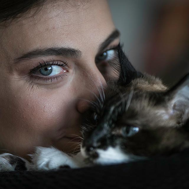 Mulher com um gato próximo ao rosto