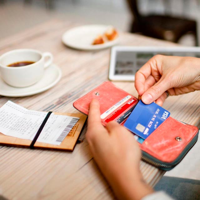 Pessoa retirando cartão da carteira para fazer pagamento num café