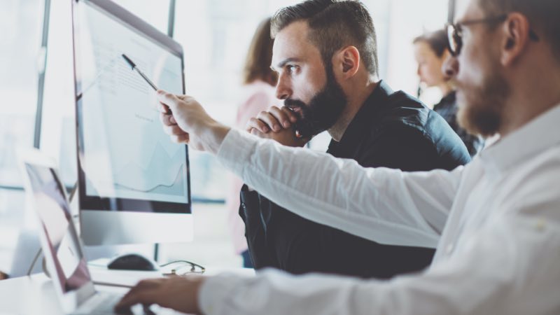 Dois homens trabalhando juntos em frente ao computador