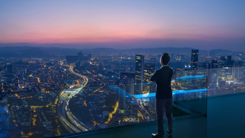 Executivo no topo de um prédio alto observando a cidade