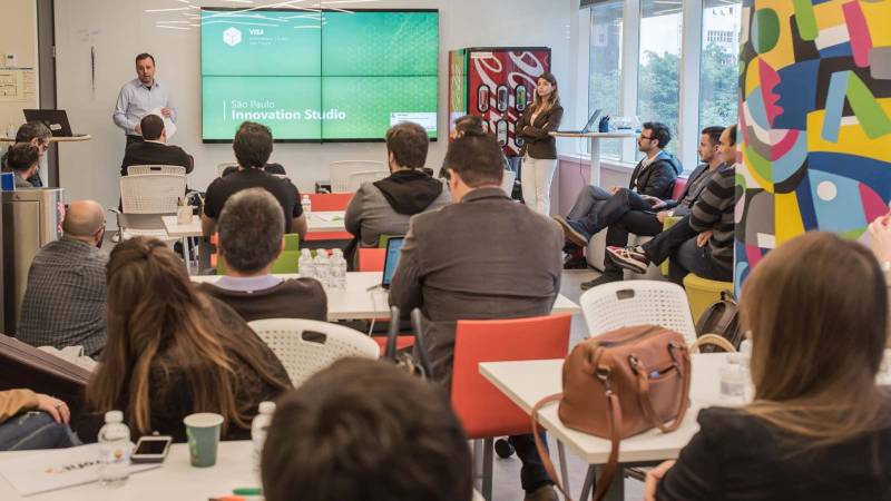 Visa Innovation Studio Sala de escritório moderno repleta de pessoas assistindo a uma palestra