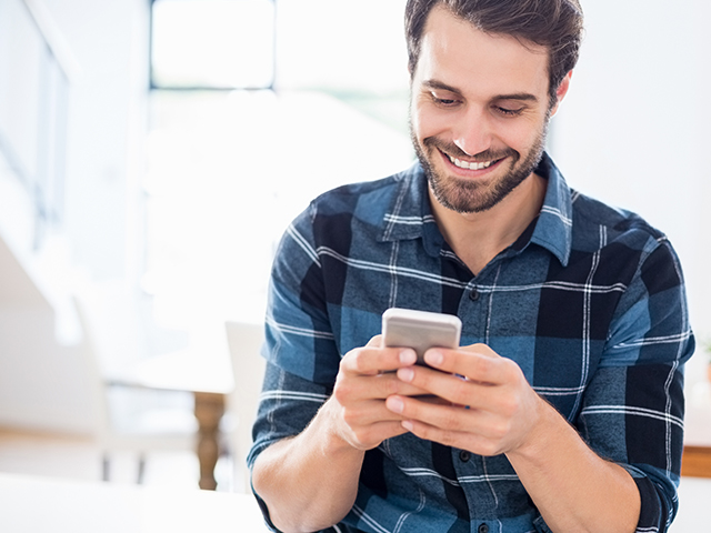 Homem sorri para o celular