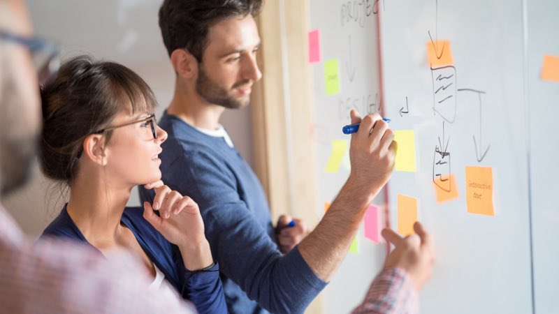 Equipe analisando e escrevendo sobre post-its colados na janela