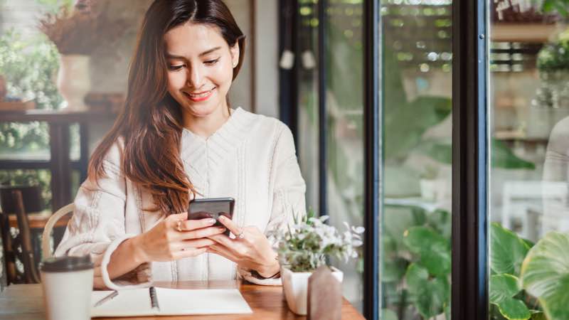 Mulher num café mexendo no smartphone