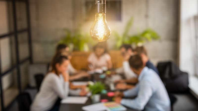 Startup Lâmpada acesa em foco sobre reunião de trabalho