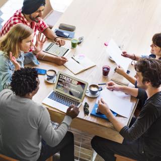 Equipe de trabalho se reúne com cadernos e notebook para conversar