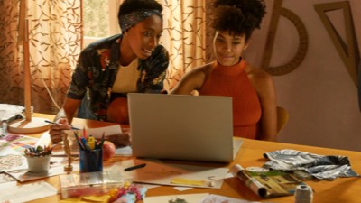 Duas mulheres num ateliê com um notebook
