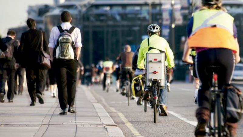 Imagem de uma rua movimentada com ciclovia e pedestres