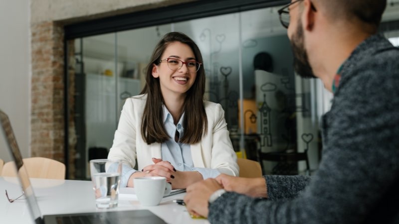 Mulher de perfil executivo sorrindo e conversando num café