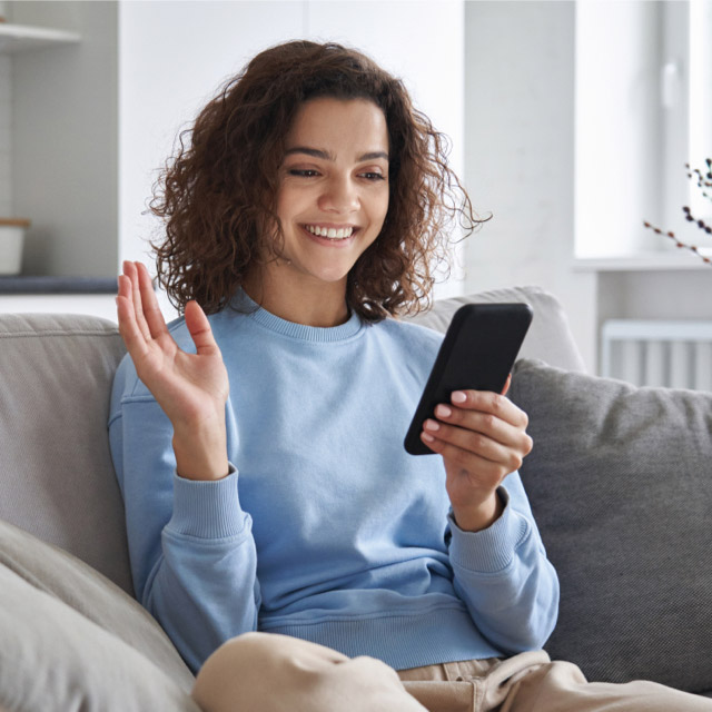 Imagem exibe mulher sorrindo enquanto usa um celular
