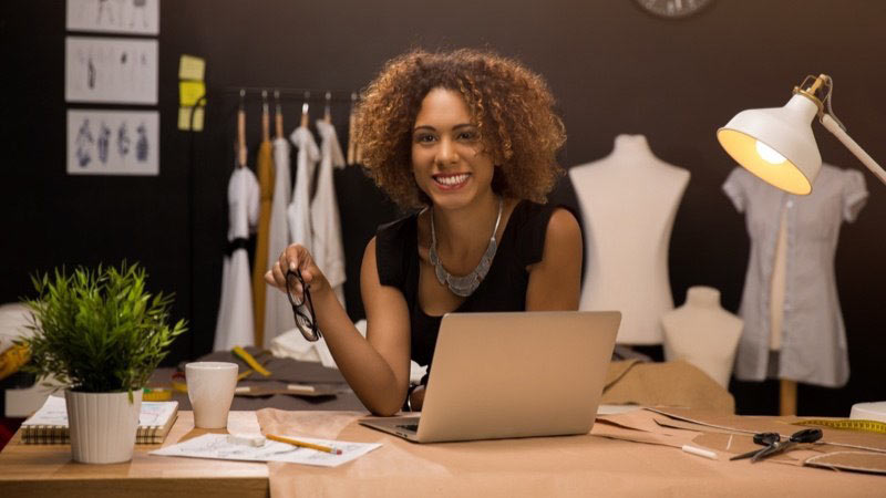 Fotografia de uma mulher sorrindo em frente ao computador