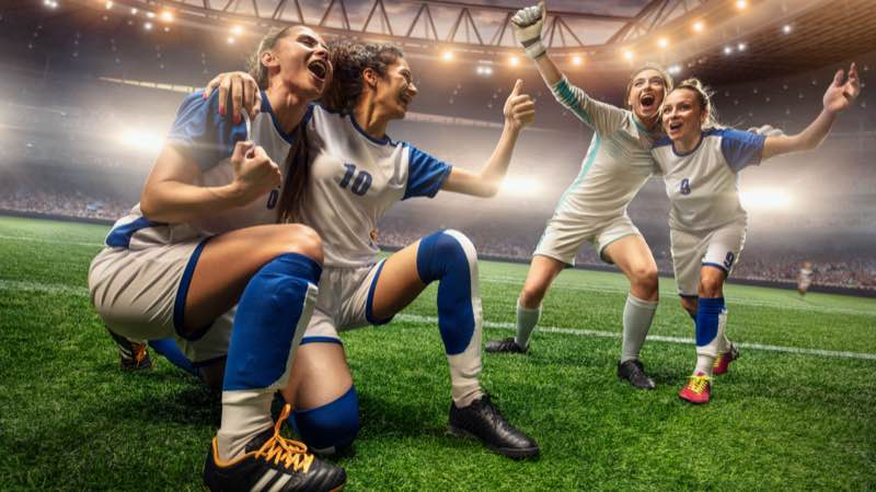 Imagem de jogadoras comemorando em um estádio de futebol