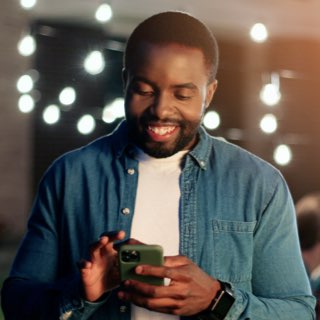 Imagem de um homem sorrindo utilizando seu smartphone