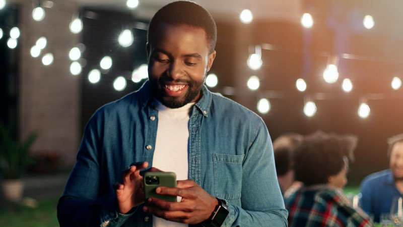 Imagem de um homem sorrindo utilizando seu smartphone